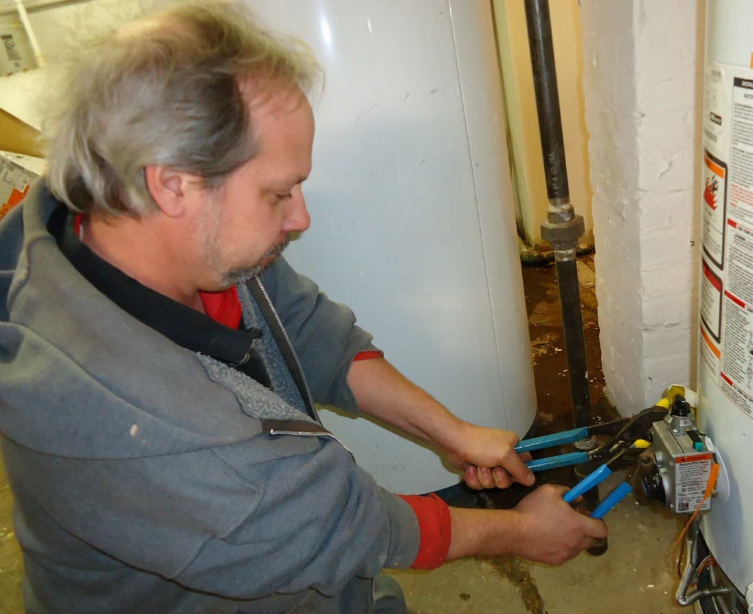 Tradesperson servicing a gas hot water unit