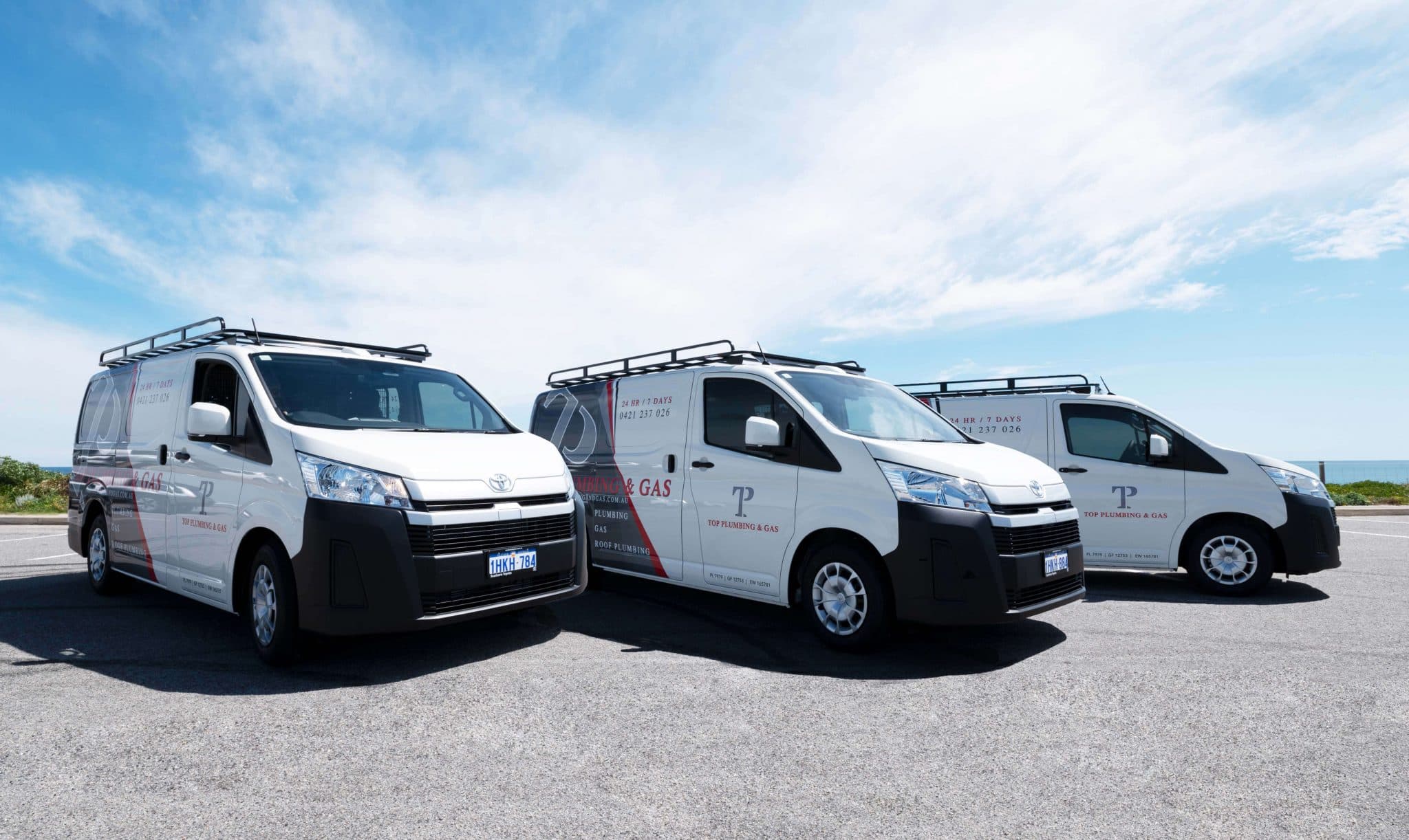 Three liveried Top Plumbing and Gas vans parked together with the Perth coast in the background